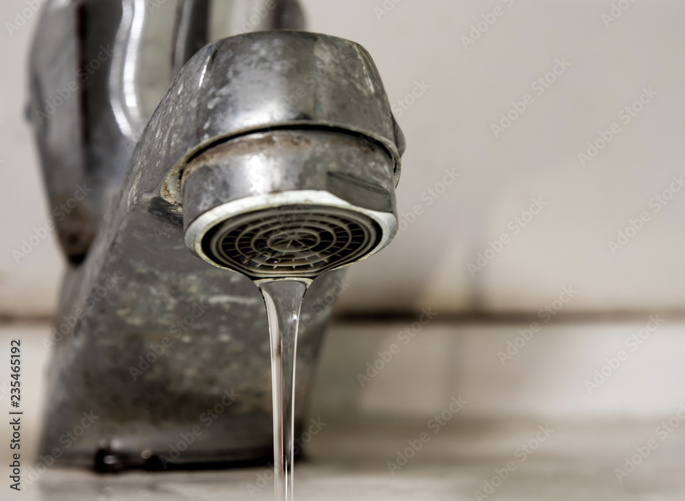 Leaking water drops from old rust and stained faucet Leaking water drops from old rust and stained faucet