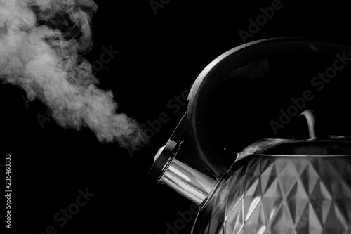 Boiling steel kettle on a black background.