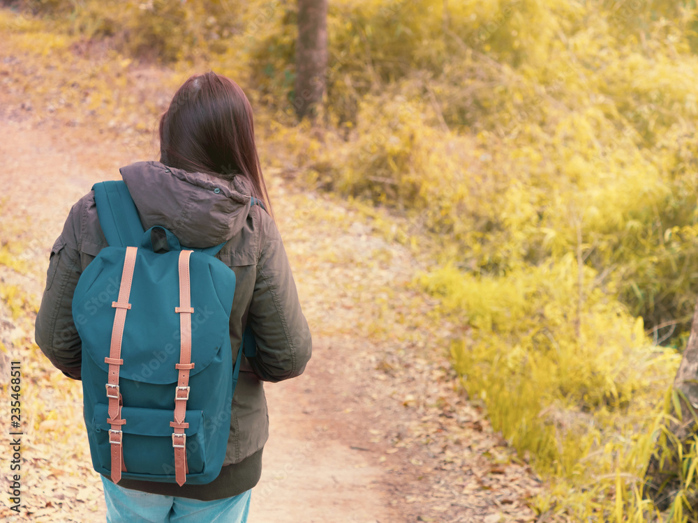 solo backpack and camping concept from backside of long hair woman in warm  hoodie sweatshirt with