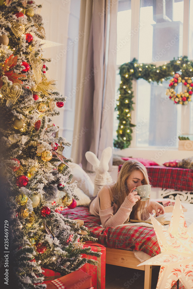 young woman in christmas interior. Sit with a plaid and a cup of tea.