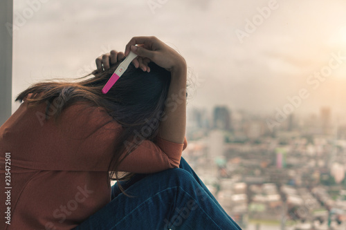 Photography Unhappy young asian woman holding pregnancy test showing a positive result, Wellness and healthy concept, Abortion problem, Selective focus