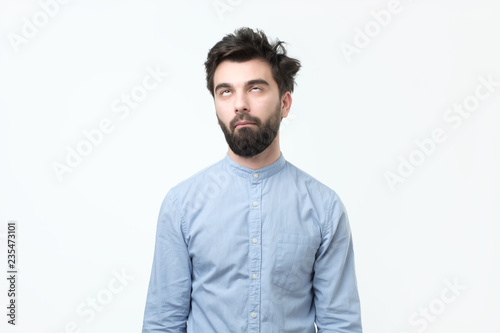 Weary hispanic man in blue shirt rolling his eyes up. He is exhausted with work or tired of listening his wife chatting. photo