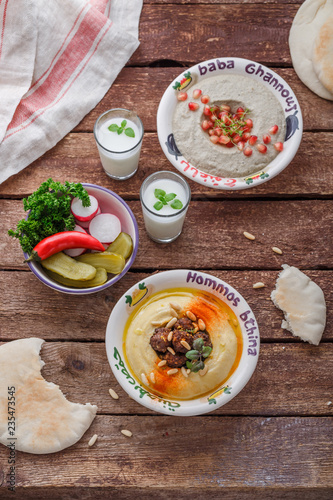 Traditional lebanon appetizers hummus, baba ganoush, vegetables and ayran, rustic.