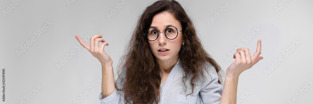 Obraz premium Young brunette girl with glasses. The girl spread her hands to the sides.