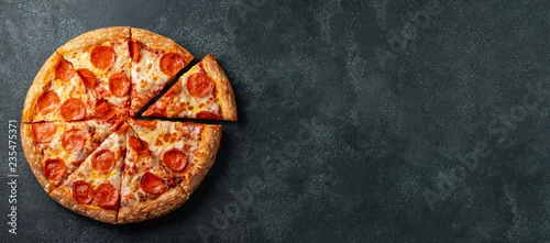 Obraz  z motywem Tasty pepperoni pizza and cooking ingredients tomatoes basil on black concrete background. Top view of hot pepperoni pizza. With copy space for text. Flat lay. Banner