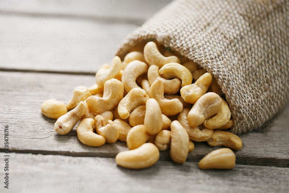Cashew nuts in burlap bag on wooden gray background . Healthy food Cashew nuts in burlap bag on wooden gray background . Healthy food