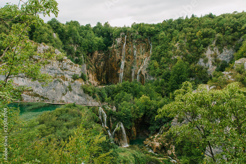 Travel to Croatia. Plitvice Lakes is a popular Croatian national park of incredible beauty. Photo of a favorite point among tourists - a stunning waterfall surrounded by greenery © scoutori