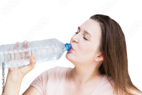 Young woman drinking water from bottle on white background. Girl holding bottle in hand