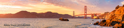 Panoramic view of famous Golden Gate Bridge seen from Baker Beach in beautiful golden evening light. San Francisco, California, USA