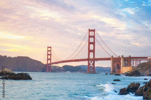 Classic panoramic view of famous Golden Gate Bridge seen from Baker Beach in beautiful golden evening light. San Francisco, California, USA