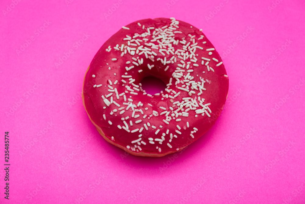 Pink donut with colorful sprinkles isolated on pink background. Top view. Pink donut with colorful sprinkles isolated on pink background. Top view.