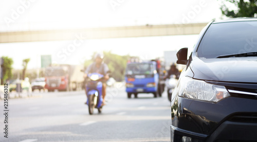 Wallpaper Mural Focusing on the Dark Gray car headlights on a street corner with sunlight flares, In the background, the driver, bike and car. Closeup headlights of car. Copy space for insert text. Torontodigital.ca