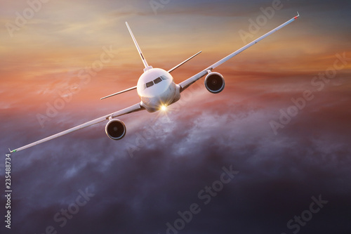 Commercial airplane flying above dramatic clouds.