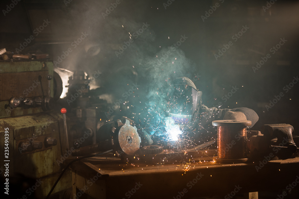 Welder is welding metal part in factory Welder is welding metal part in factory