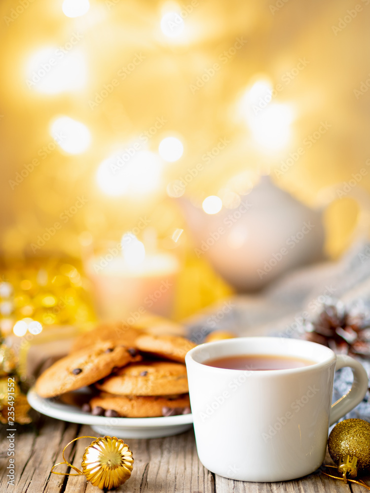 Christmas background with Chocolate chip cookies, cup of tea. Cozy evening, mug of drink, Christmas decorations, candles and lights garlands Christmas background with Chocolate chip cookies, cup of tea. Cozy evening, mug of drink, Christmas decorations, candles and lights garlands