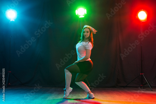 Modern dance, sport and people concept - young woman dancing jazz funk in the darkness under colourful light