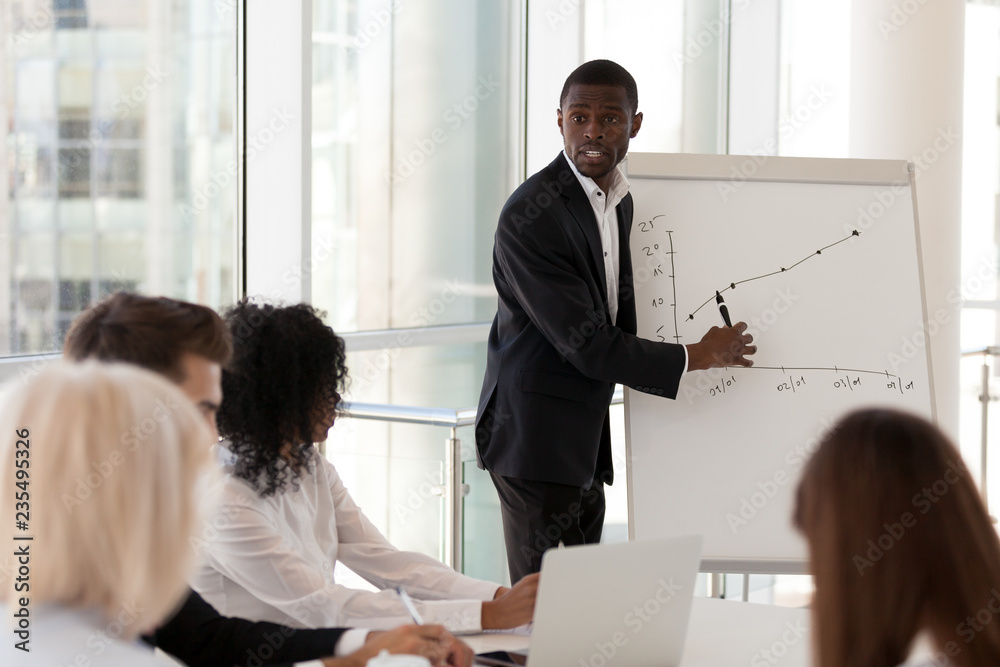 Serious african american mentor giving presentation explains sales growth  graph training diverse team interns at group meeting, black business coach  speaking explain new corporate plan on flipchart Photos | Adobe Stock
