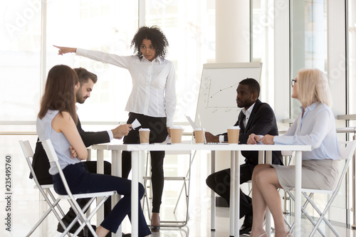 Angry mixed race manager team leader firing incompetent employee intern for bad results asking to leave group office meeting having conflict or dispute, racial discrimination at work concept