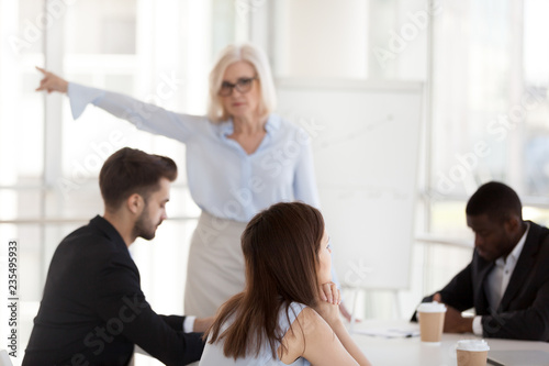 Disgruntled young employee intern ignoring mature angry executive firing incompetent worker asking to leave group office meeting, different age generations conflict, discrimination at work concept