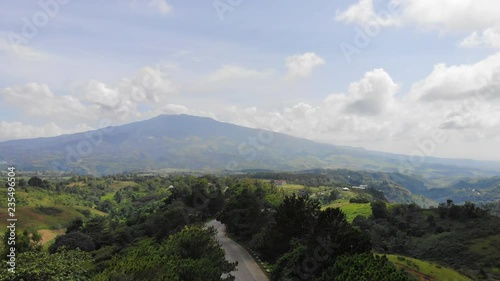 Drone shot of over a road full of pines and a background of the active volcano Mt. Kanlaon int he Philippines photo