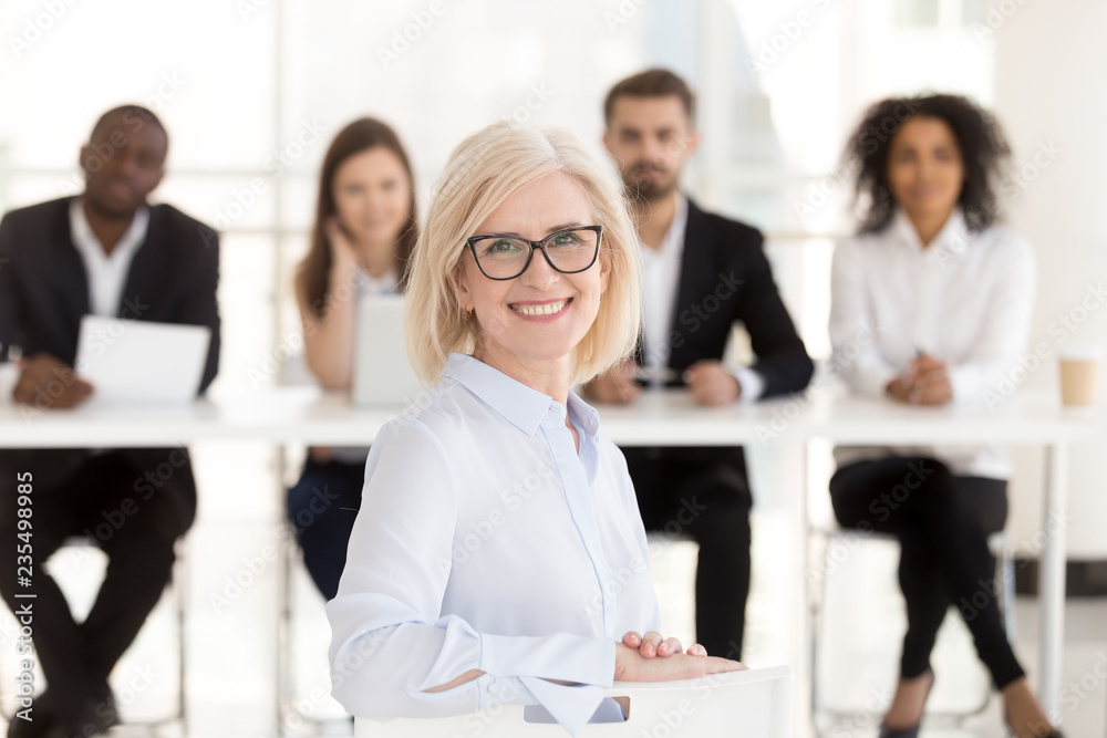 Smiling senior mature woman job applicant looks at camera at interview with hr recruiting team, happy middle aged lady business coach or vacancy candidate portrait, getting hired, employment concept Smiling senior mature woman job applicant looks at camera at interview with hr recruiting team, happy middle aged lady business coach or vacancy candidate portrait, getting hired, employment concept