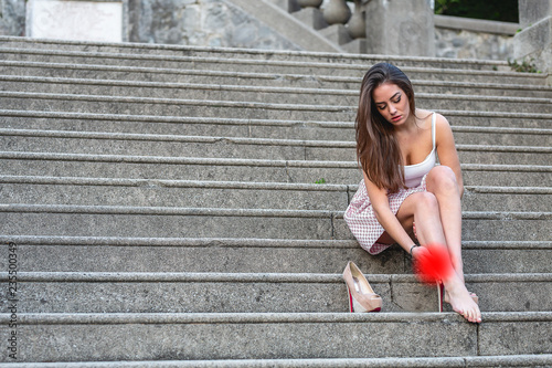 Pretty young girl is sitting on a marble stairs.