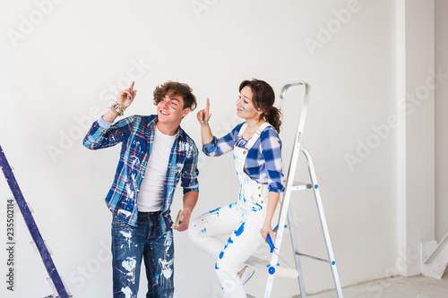 People, repair and relationship concept - Young funny couple doing renovation in new apartment