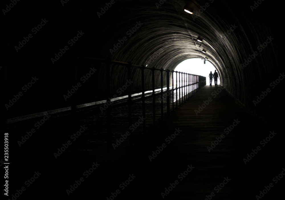 Silhouette Of A Couple In Front Of Bright Light At The End Of A Dark Tunnel