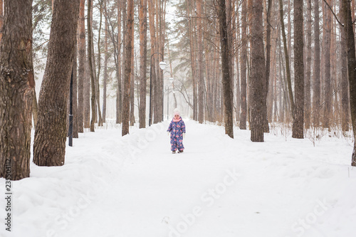 Childhood, nature and winter concept - Funny laughing toddler girl running in a beautiful snowy park