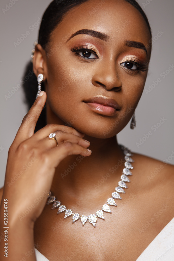 Closeup portrait of beautiful black skin woman. Charming young bride in wedding dress and jewelry.