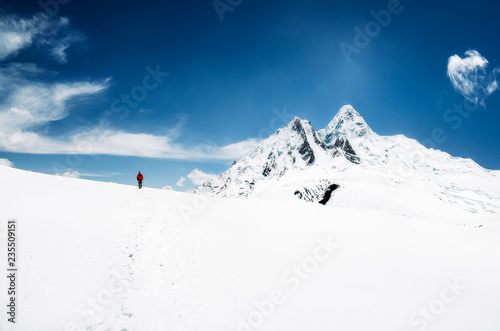 Mountain trekker in Himalayas mountains walking in snow with peaks in background, Nepal