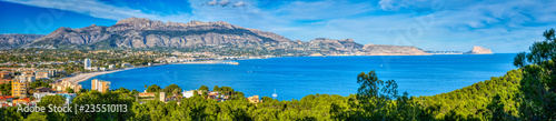 A panoramic view of Altea and the Costa Blanca from the Natural Park Serra Gelada with a bright blue ocean and sky and the mountains and towns of the surrounding area and the green trees of the park