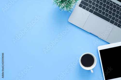 Office desk working space - Flat lay top view mockup photo of working space with laptop, smartphone, coffee up and notebook on blue pastel background. Pastel blue color background working desk concept photo