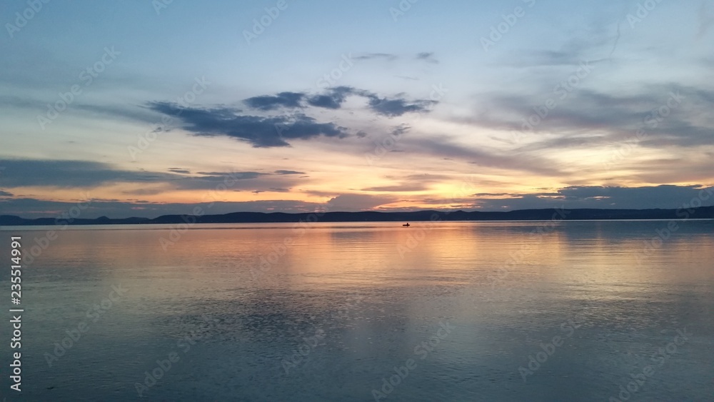 Breathtaking sunset at lake Balaton with a small boat afar