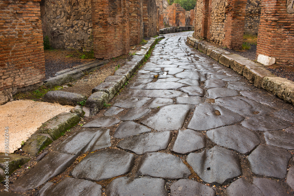 wet stone road between buildings in in Pompei in Italy