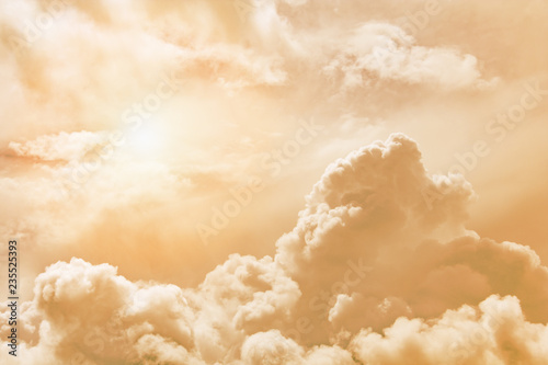 Fluffy clouds illuminated by the sun against a orange sunset sky (background, toned)