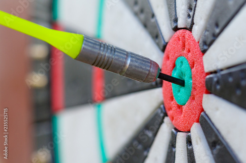 View on a fragment of dartboard with dart in a bullseye (shallow depth of field, concept)