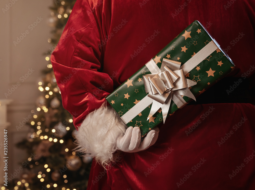 Fototapeta Święty Mikołaj trzyma boże narodzenie prezent za jego plecy