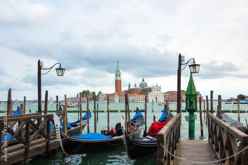 Gondolas on Canal Grande with San Giorgio Maggiore church in the background. Cloudy, rainy day. Venice, Italy.