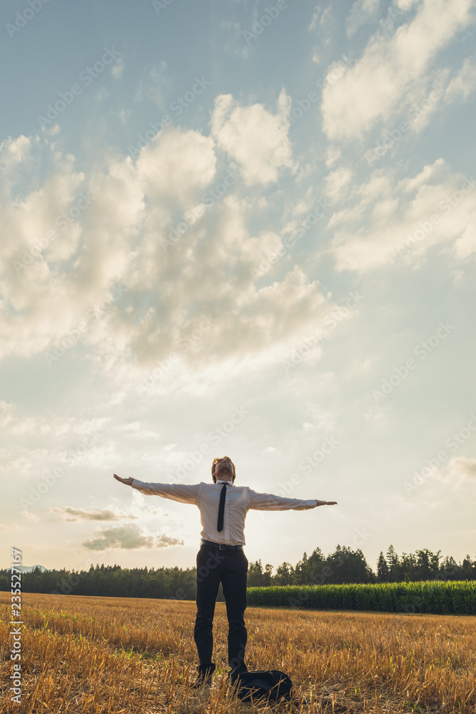 Businessman with his arms wide open standing under cloudy evening sky Businessman with his arms wide open standing under cloudy evening sky