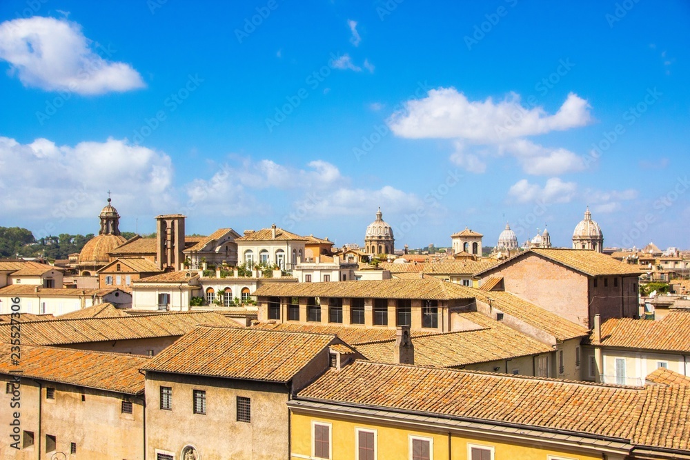 View on the old red roofs of Rome. Rome historic center skyline with old domes and clouds, seen from Capitoline Hill. Bright, warm, sunny summer day on Rome. Italy.