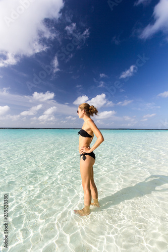 junge Frau im Bikini steht im klaren Wasser auf den Malediven © marksn.media