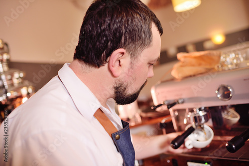 a handsome  bearded barista man holding a Holder with ground coffee. Making coffee in a coffee house