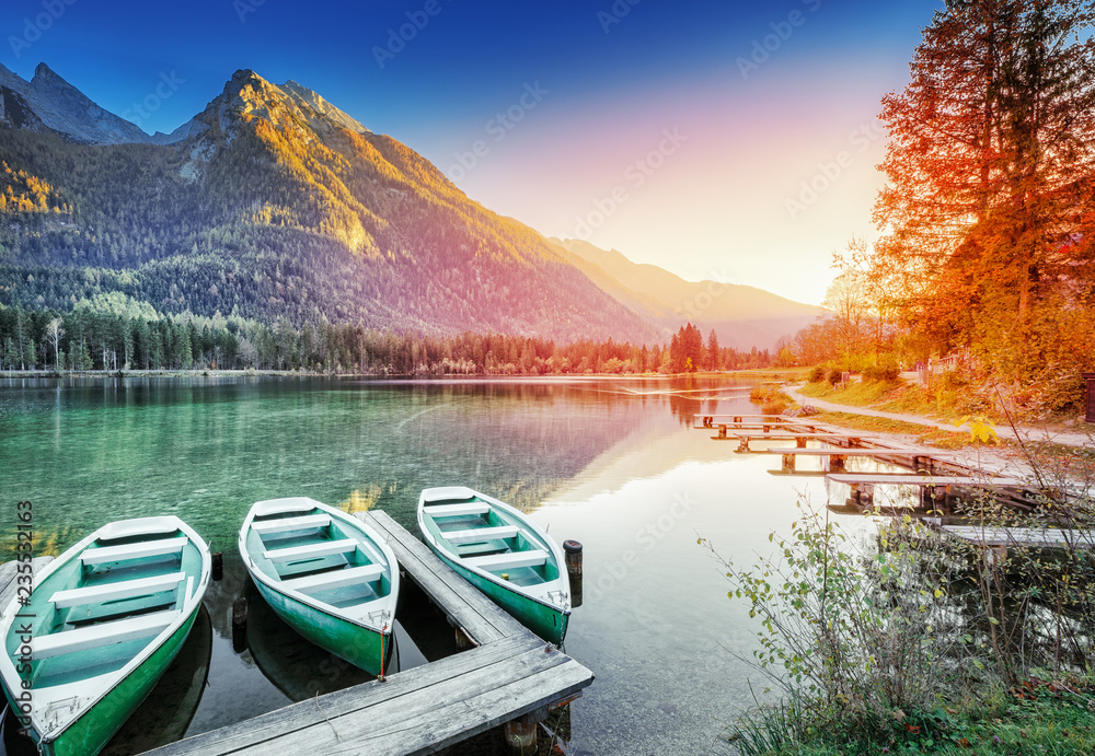 Fototapeta premium Zakotwiczone łodzie na jeziorze Hintersee - malownicze krajobrazy zachodu słońca alpejskiej przyrody w Niemczech, Bawarii, Europie. Jesienny krajobraz. Szczyty górskie w tle, Park Narodowy Berchtesgaden, Ramsau.