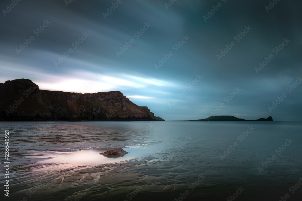 Long exposure on the clouds at Rhossili Bay and Worms Head on the Gower peninsula, Swansea, South Wales, UK