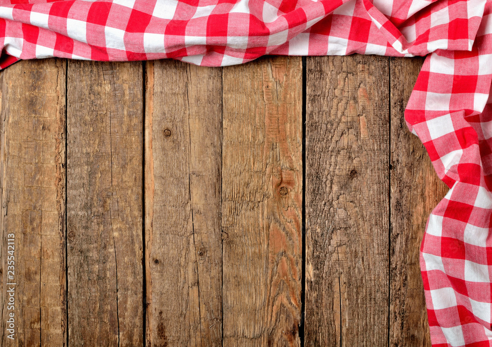 Red checkered tablecloth top and right frame on vintage wooden table background - view from above Red checkered tablecloth top and right frame on vintage wooden table background - view from above