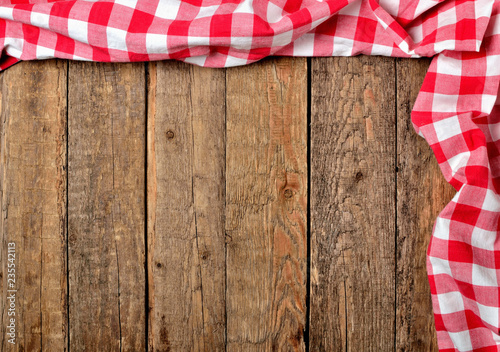 Red checkered tablecloth top and right frame on vintage wooden table background - view from above