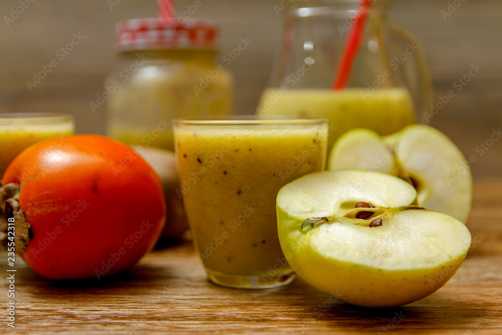 Freshly blended fruit smoothie with fresh fruits on wooden table with raw fruits