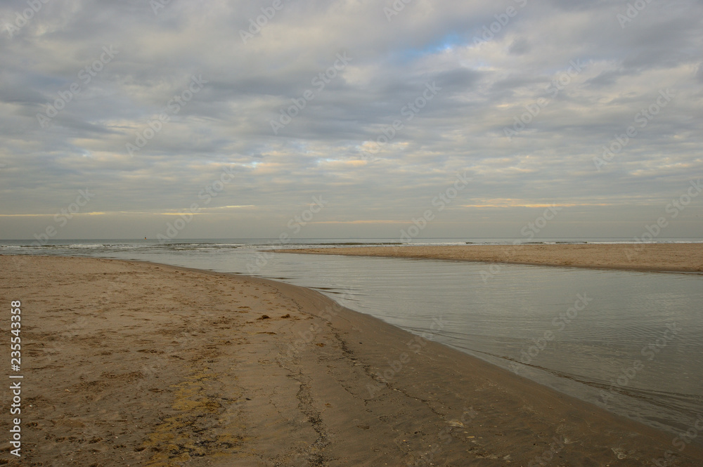 Nadmorskie wybrzeże, plaża i morze pod niebieskim niebem z chmurami.