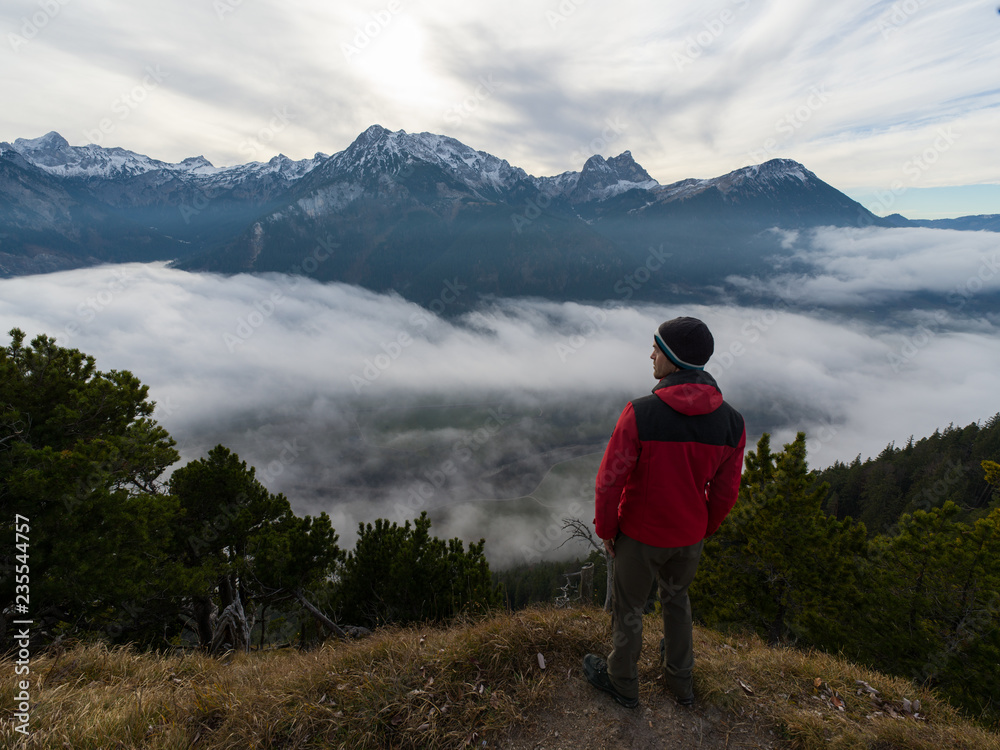 Hiker with red jacket overlooking foggy valley - Fall/Autumn season
